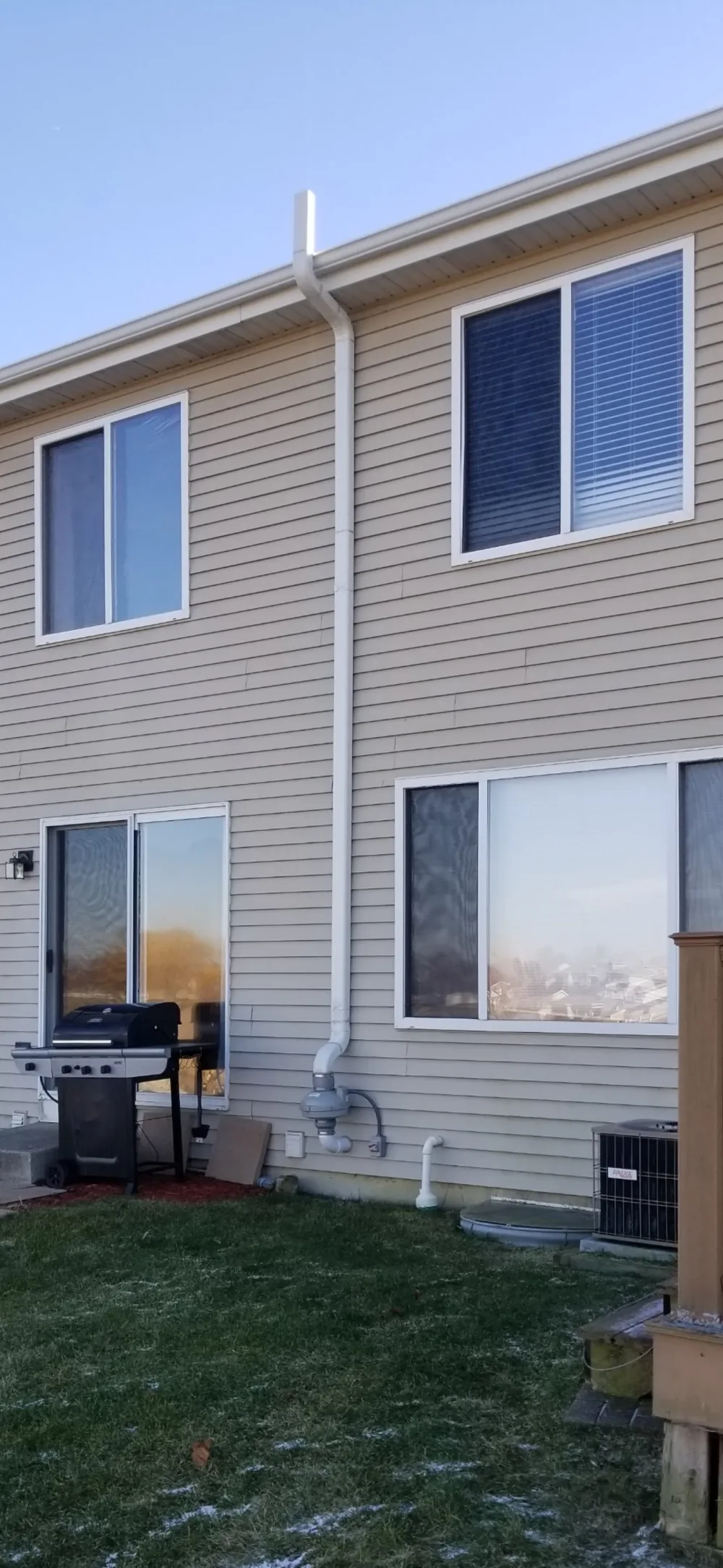 Townhouse exterior in winter with white PVC radon pipe rising above the roofline.