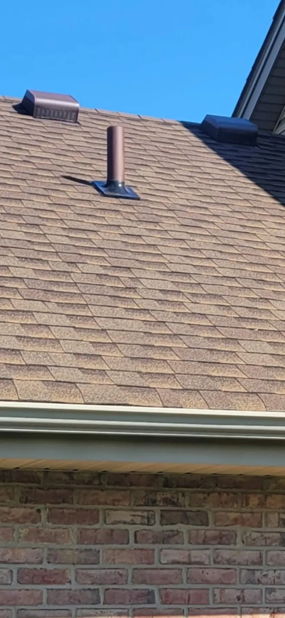 Radon system pipe termination above the shingles, painted to match the shingle color.
