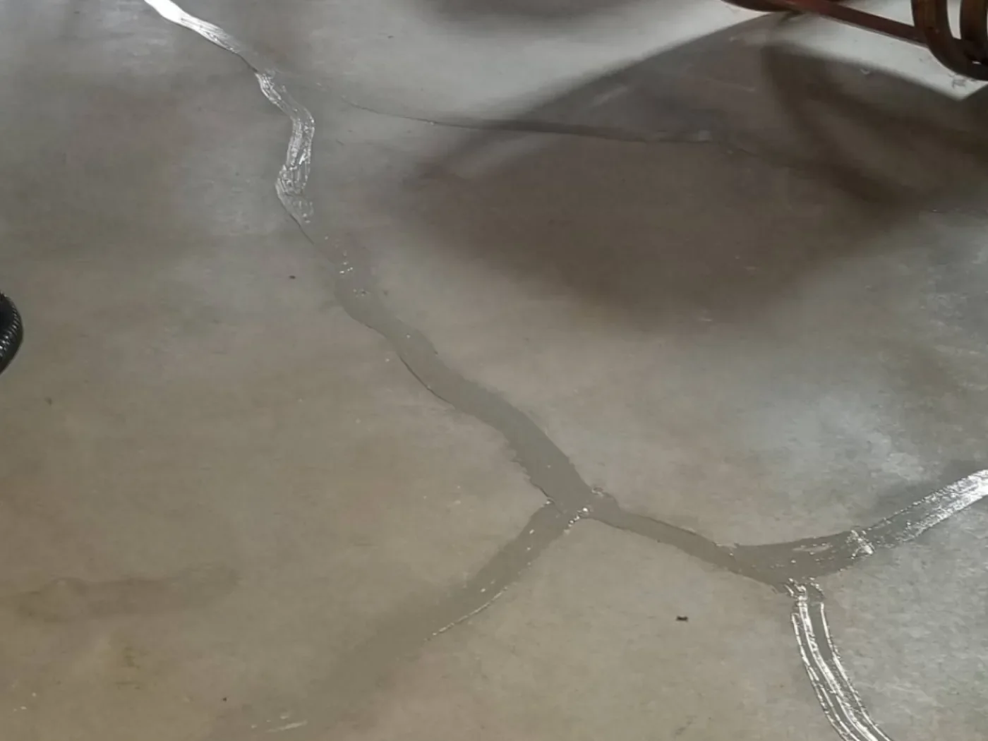 Basement slab with visible cracks fully sealed with aluminum-grade radon caulking.