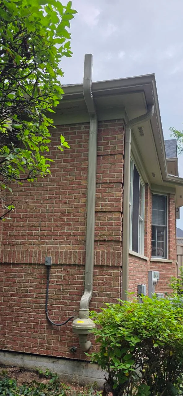 Exterior radon fan and trim-colored venting beside a brick home in Lemont