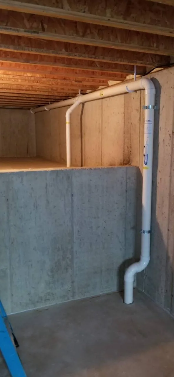 Radon piping along an unfinished basement wall and below floor joists in Naperville