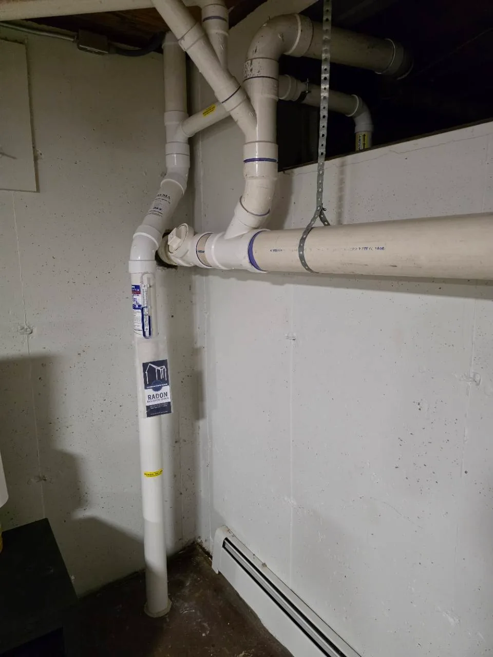 Radon pipe beside existing sewer plumbing, with a branch connection, at a New Lenox home